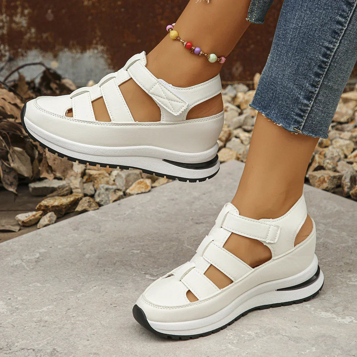 White platform sandals with sporty straps, closed toe, and casual fit, worn with jeans.