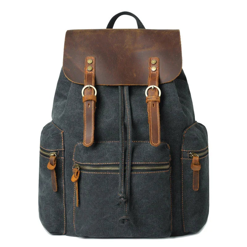 Dark canvas backpack with brown leather flap and straps, front zip pockets, vintage style