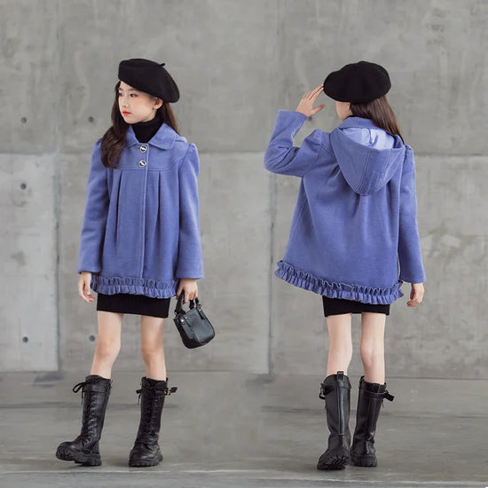 Girl wearing a loose-fit purple hooded coat with ruffle trim, black dress, and tall lace-up boots