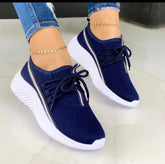 Navy blue mesh sneakers with white soles and laces, worn with ripped skinny jeans