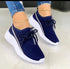 Navy blue mesh sneakers with white soles and laces, worn with ripped skinny jeans