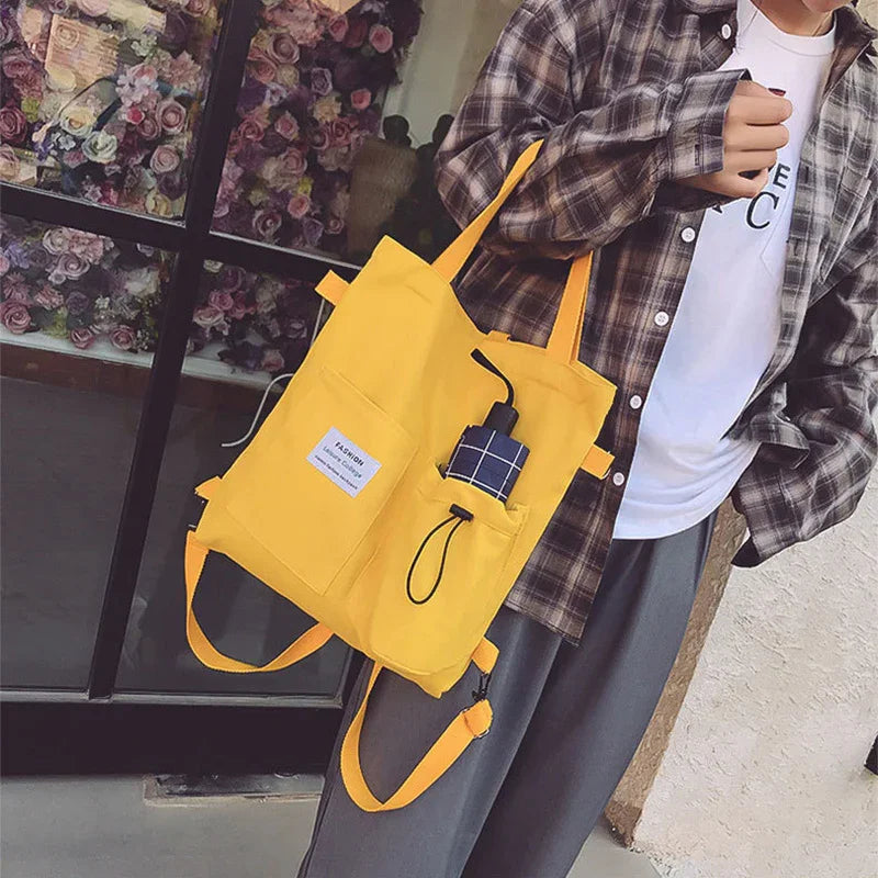 Person wearing a relaxed-fit plaid shirt over a white tee, gray pants, and carrying a yellow canvas tote bag with front pockets.