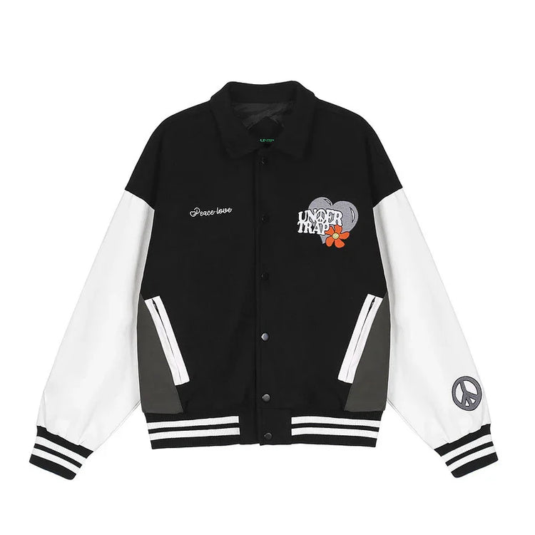 Black and white varsity jacket with embroidered graphics, striped cuffs, relaxed fit.