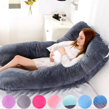 Woman in white nightdress relaxing on a large grey velvet U-shaped body pillow on bed