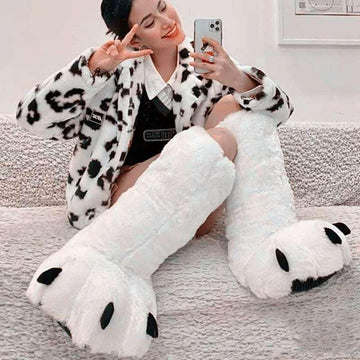 Woman wearing a faux fur animal print jacket and fluffy white paw slippers, cozy fit