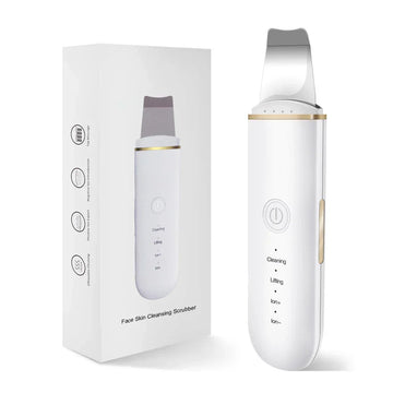 White face skin cleansing scrubber with gold trim, sleek ergonomic design, next to packaging box.