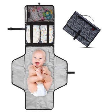 Portable diaper changing pad in gray with pockets for baby essentials, displayed open with a baby in a diaper lying on it; includes folded view showing compact, patterned case.