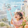 Little girl in pink lace dress holding magic wand spray toy, smiling outdoors near roses