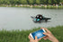 Person using smartphone to control a black and teal remote control boat on a lake