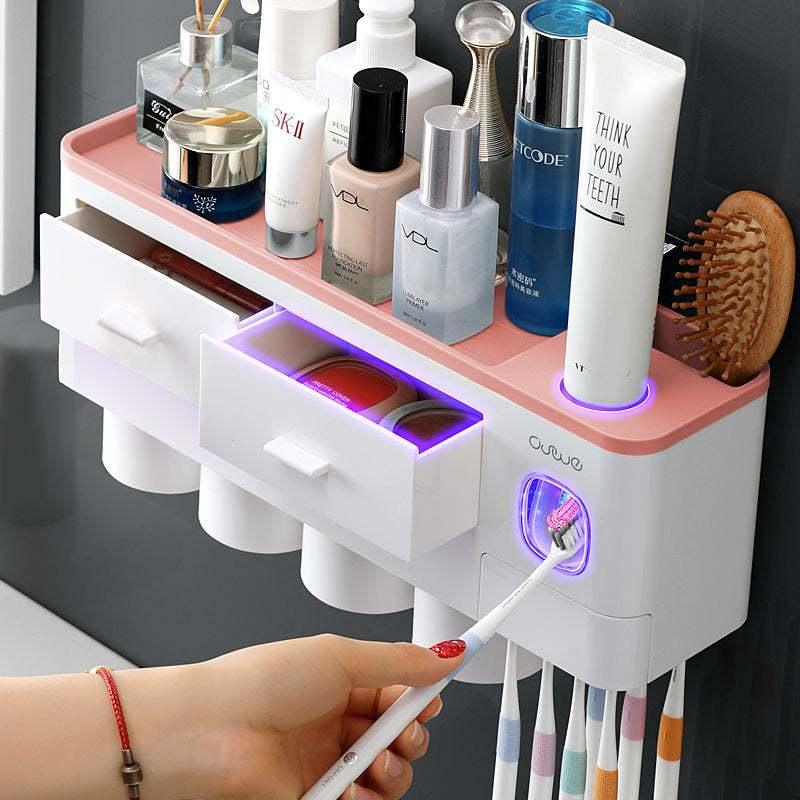 Wall-mounted bathroom organizer with white and pink plastic, storage drawers, cup holders, and skincare products.