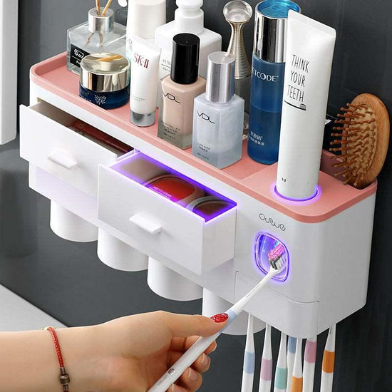 Wall-mounted bathroom organizer with white and pink plastic, storage drawers, cup holders, and skincare products.