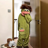 Person wearing oversized green plush onesie with cartoon face, relaxed fit, and fuzzy hood.