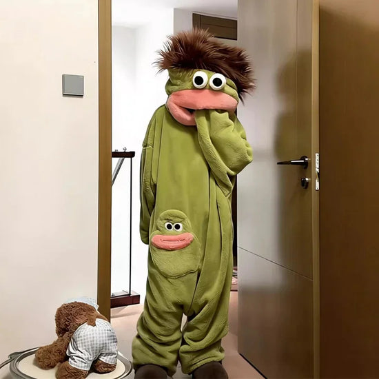 Person wearing oversized green plush onesie with cartoon face, relaxed fit, and fuzzy hood.