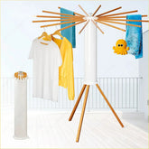 Modern folding clothes rack with wooden arms, displaying white t-shirt, yellow jacket, blue jeans.