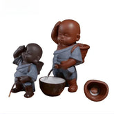 Two ceramic figurines in blue textured robes with relaxed fit, holding brown baskets and accessories.