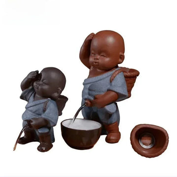Two ceramic figurines in blue textured robes with relaxed fit, holding brown baskets and accessories.