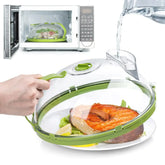 Microwave food steamer with clear plastic dome and green accents, cooking salmon and vegetables