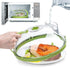 Microwave food steamer with clear plastic dome and green accents, cooking salmon and vegetables