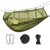Olive green nylon hammock with mosquito net, carabiners, strap, and rope for outdoor camping.