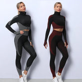 Two women in fitted seamless colorblock athleisure sets with long sleeve crop tops and leggings, in grey-black and burgundy-black.