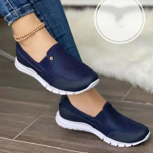 Navy blue slip-on mesh sneakers with white soles, casual fit, worn with denim jeans.