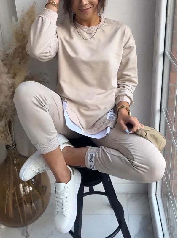 Woman in beige oversized sweatshirt and joggers set with white sneakers, casual streetwear style