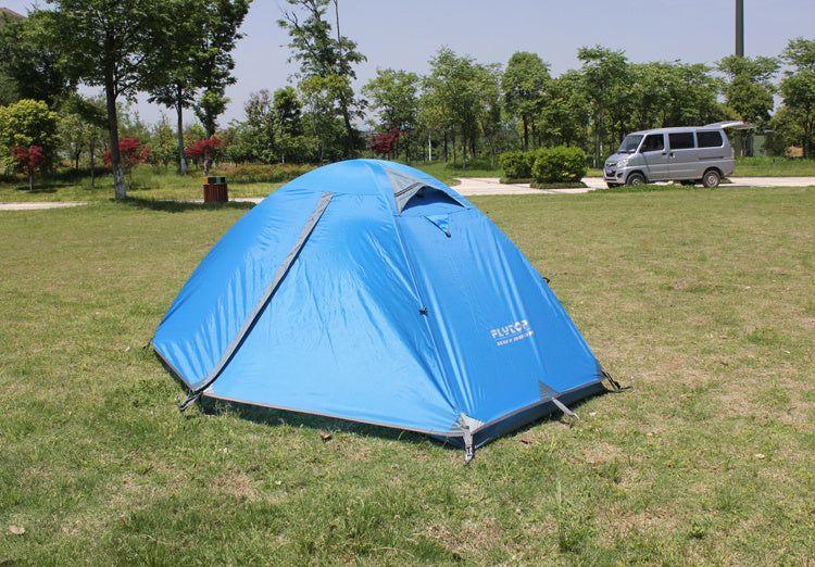Blue dome-shaped outdoor tent with waterproof fabric set up on grassy field