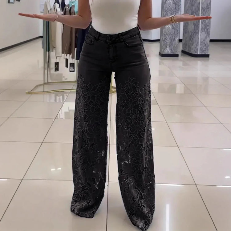 Woman wearing black wide-leg floral lace pants and a fitted white sleeveless top indoors
