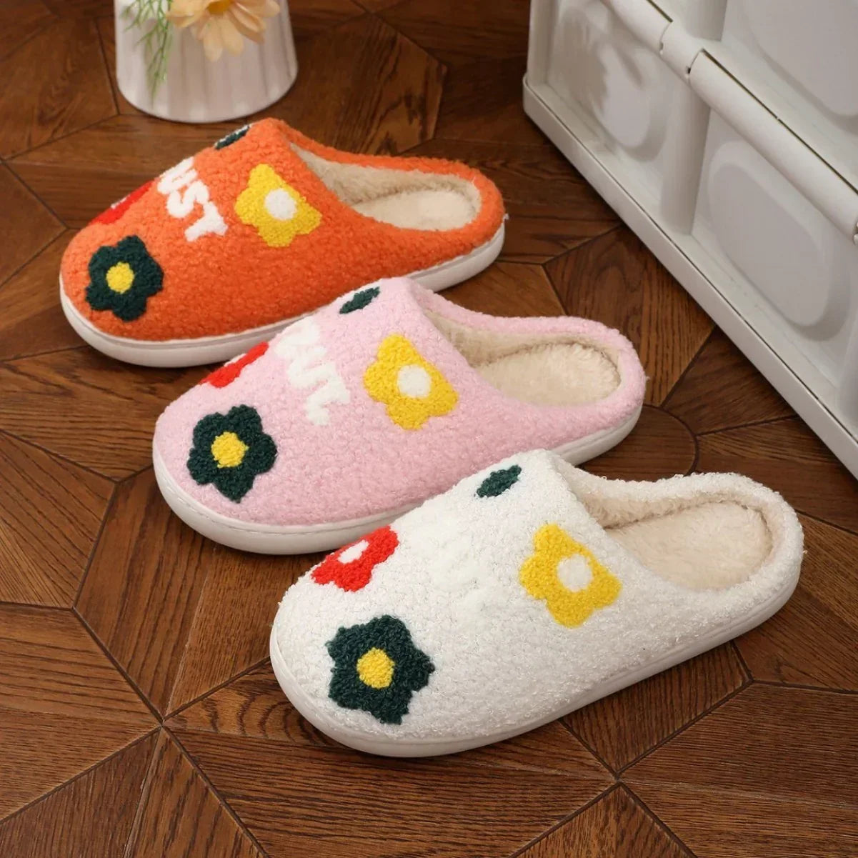 Colorful plush slippers with floral pattern, fleece material, and cozy slip-on fit on wood floor