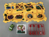 Yellow dinosaur-themed play mat with road track, green toy car, stickers, and red traffic sign pieces.