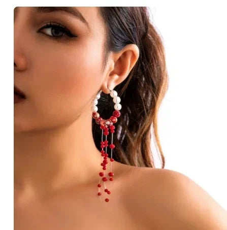 Woman wearing a statement hoop earring with pearl and red bead details, minimalist style