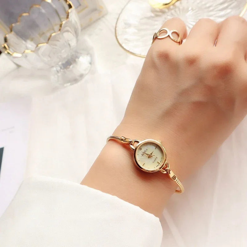 Minimalist gold wristwatch with round dial and slim metal band, styled on wrist, elegant fit
