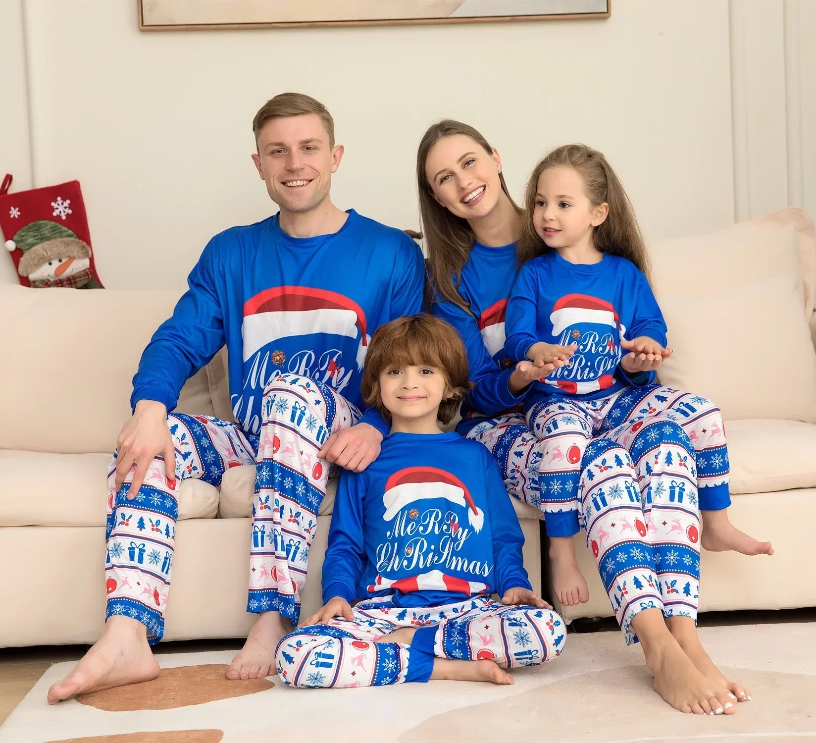 Family in blue and white matching Christmas pajama sets with festive print, relaxed fit.