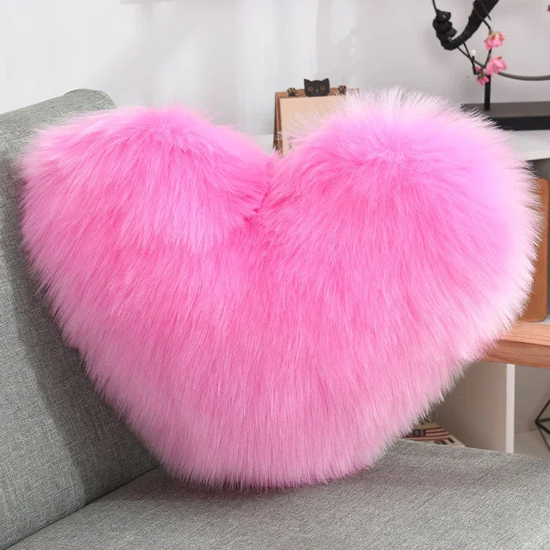 Fluffy heart-shaped pillow in bright pink faux fur on a modern gray sofa