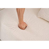 Hand pressing into soft, textured beige fabric sofa with matching cushion