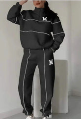 Woman wearing black streetwear tracksuit with white piping, relaxed fit, high collar