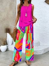 Woman wearing a sleeveless hot pink top with loose, wide-leg, multicolor abstract print pants.