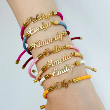 Stack of colorful cord bracelets with gold nameplate charms on wrist, adjustable fit
