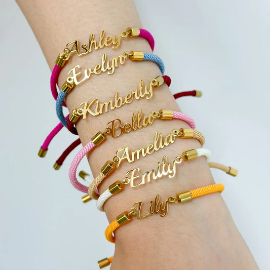 Stack of colorful cord bracelets with gold nameplate charms on wrist, adjustable fit