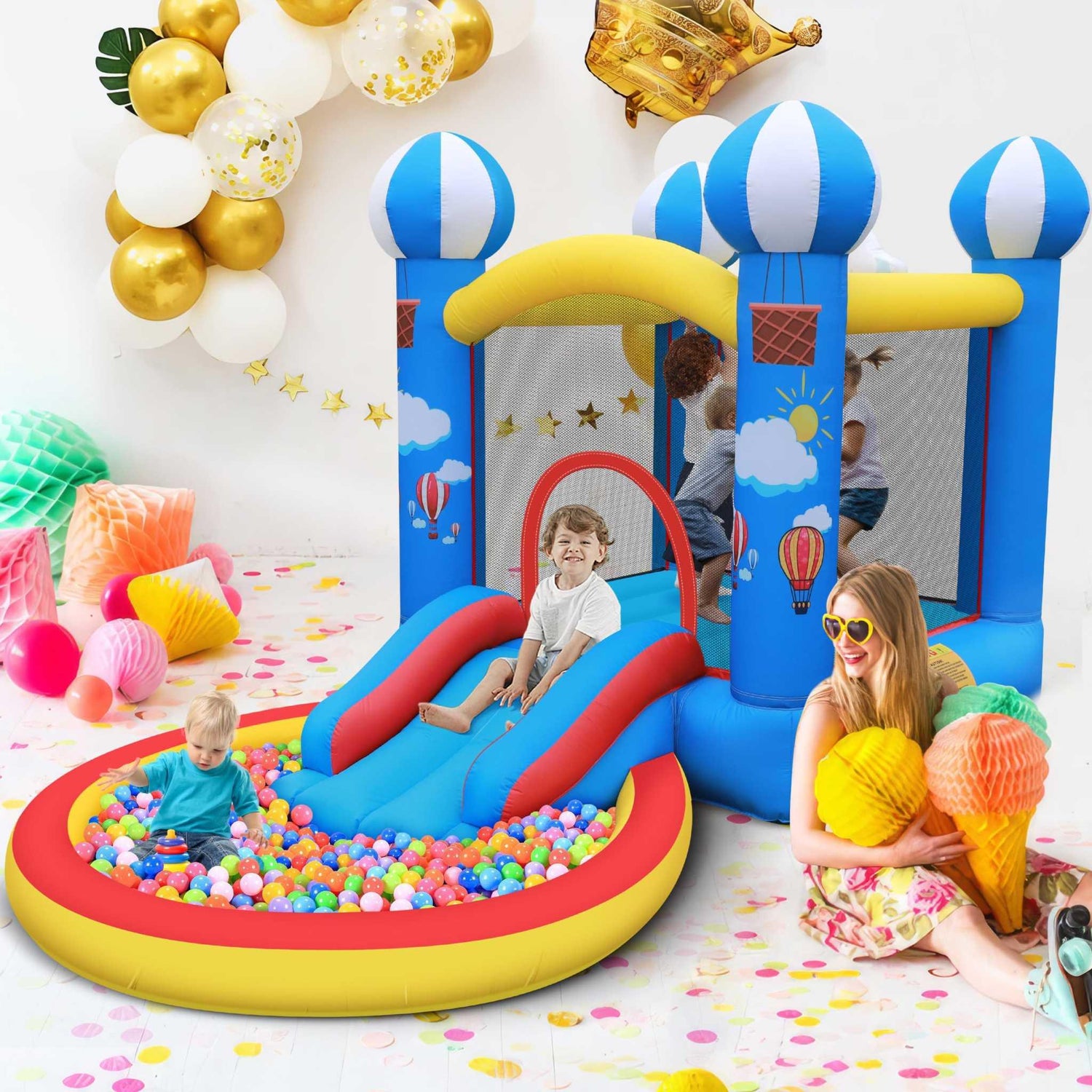Bright blue inflatable bounce house with hot air balloon designs, mesh sides, slide, and attached ball pit, kids playing inside, colorful party decor, casual fun outfits.