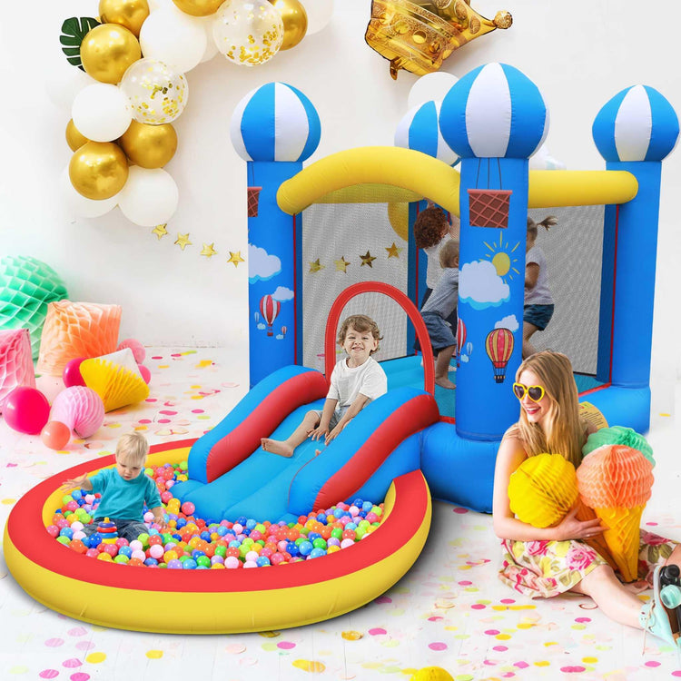 Bright blue inflatable bounce house with hot air balloon designs, mesh sides, slide, and attached ball pit, kids playing inside, colorful party decor, casual fun outfits.
