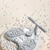 Modern white and gray foot massager with ergonomic handle and textured pads on beige background