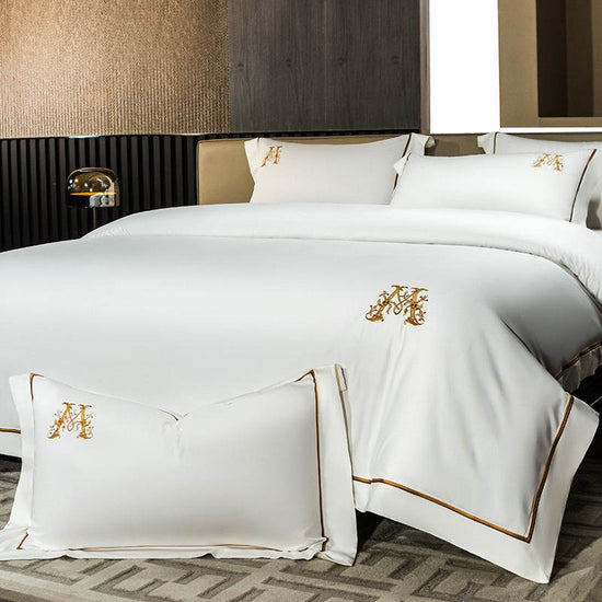 white cotton embroidery match sets bedding four-piece set with gold monogram and trim on bed and pillows