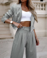 Woman wearing a gray pinstripe suit with cropped blazer and wide-leg trousers, white ribbed crop top