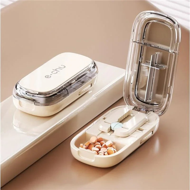 Compact beige pill organizer with pill cutter, clear lid, and assorted tablets inside
