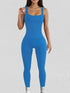 Woman wearing a bright blue ribbed sleeveless jumpsuit with a bodycon fit and scoop neckline