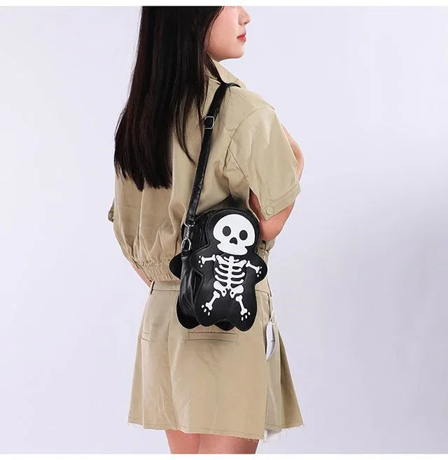 Woman in a beige short-sleeve romper carrying a black faux leather skeleton crossbody bag