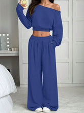 Woman in blue off-shoulder lounge set with wide-leg pants, relaxed fit, soft knit fabric.