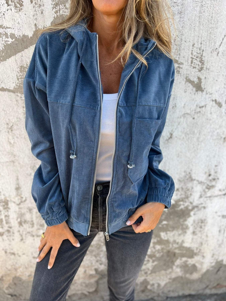 Woman wearing a loose-fit blue corduroy jacket with zipper, white tank top, and black jeans