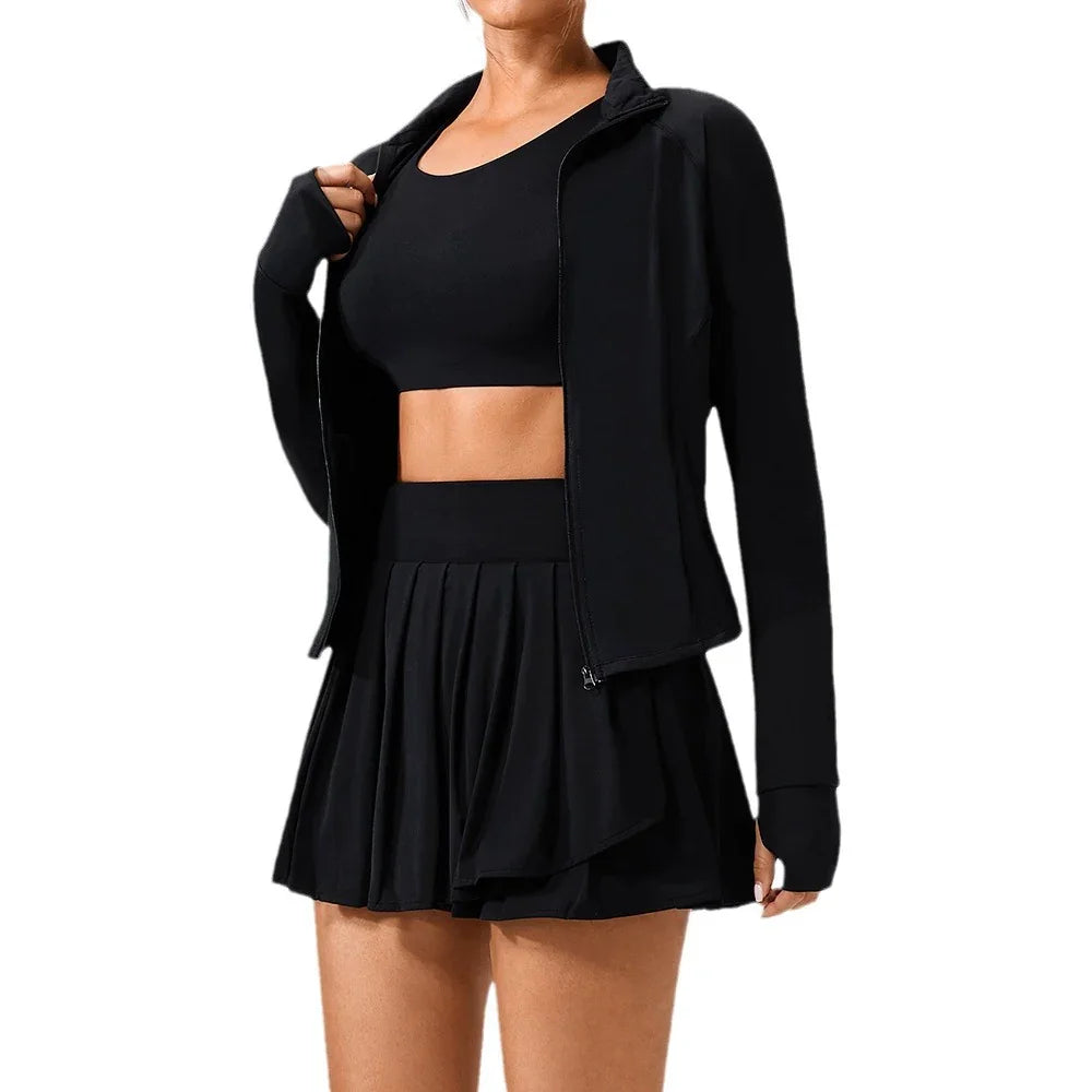 Woman wearing black crop top, pleated mini skirt, zip-up jacket, fitted activewear style